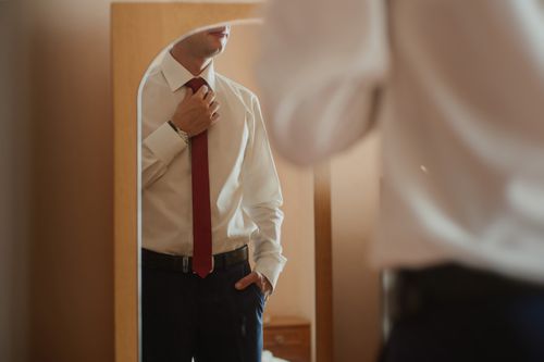 man adjusting his tie in the mirror