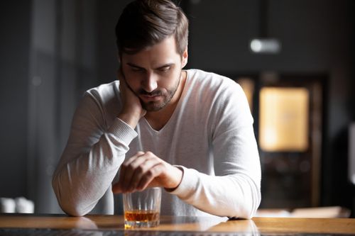 A young man at a bar experiencing alcohol withdrawal symptoms