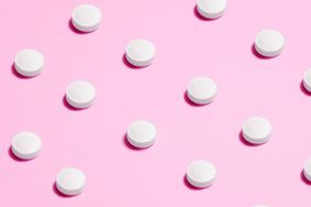 birth control pills against a pink background