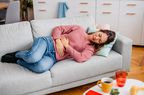 woman laying down on her couch having stomach pain 