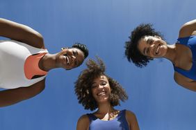 Directly below portrait of happy female athletes in sportswear against blue sky on sunny day. best-tank-tops