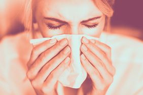 woman sneezing in tissue blowing nose flue cold nose runny-nose