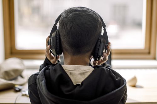 Rear view of boy with headphones at home