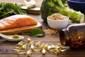 Foods rich in omega-3 fatty acids are displayed on a wooden table, including fish oil capsules, olives, salmon, flax seed