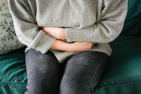 Woman wearing jeans and sweater clutching her stomach