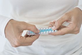 Mid section view of a woman holding a blister pack of birth control pills