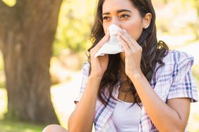 Woman blowing runny congested nose spring allergies cold symptoms