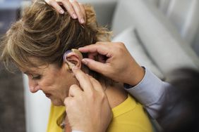 Doctor inserting hearing aid in patient's ear