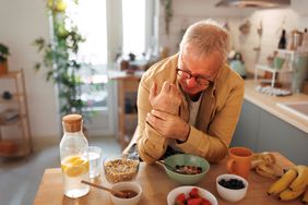 An elderly man experiencing gout pain in the kitchen