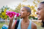 Sporty woman drinking water after exercise
