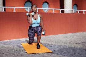Woman lifting dumb bells while lunging forward on a mat. 