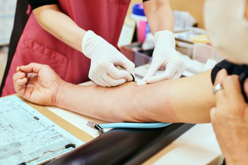 A healthcare worker draws blood from a person's arm