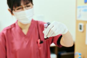 A healthcare worker holds up two test tubes of blood