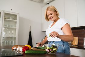 A woman prepares a salad in her kitchen