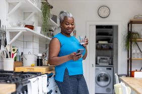 woman drinking water on cell phone