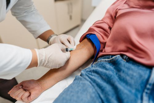 A healthcare provider draws blood from a person's arm