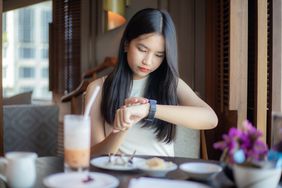 Woman having breakfast and looking at wrist watch.