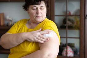 A woman puts a patch on her upper arm