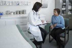 Female doctor talking to older female patient in examining room