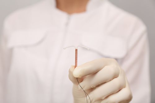 A doctor holding a copper IUD
