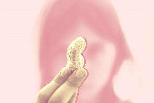 peanut-allergy-drug, A young child holds up a peanut and looks at it closely.