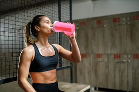 Thirsty female athlete drinking water in the gym's locker room