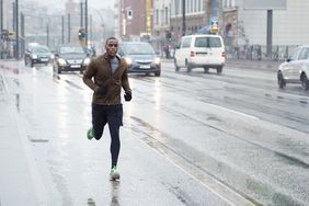 A man wearing sports clothes running through the city in the rain