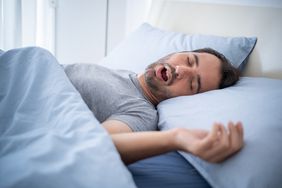man sleeping on bed while snoring 