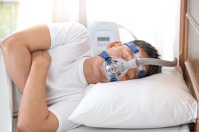 Man sleeping in bed with a CPAP machine and mask 