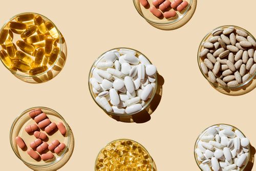 Various pills and capsules, vitamins and dietary supplements in petri dishes on a beige background.