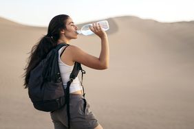 Woman traveling and drinking water in the desert