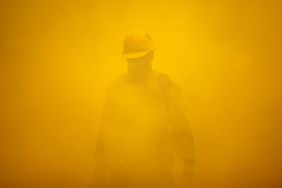 A firefighter tends to a backfire set to battle the Windy Fire on September 26, 2021 south of California Hot Springs, California. Subject is covered in thick smoke from fire.