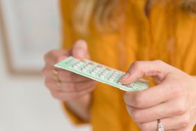 Woman taking birth control out of it's packet.