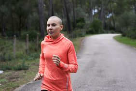Young woman with no hair from cancer treatment is running